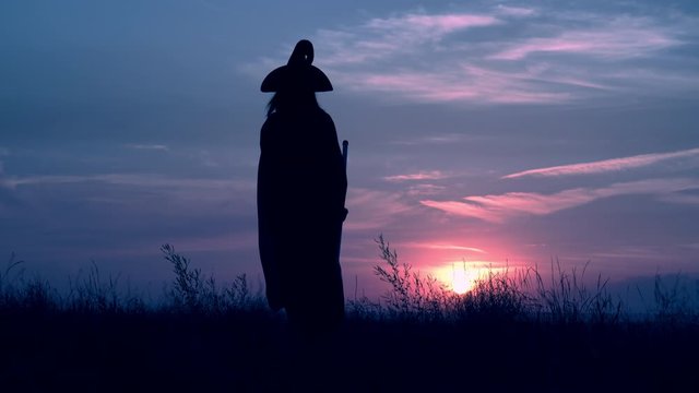 woman in a witch costume hold broom raising hands cityscape at night view on evening blue sky halloween holiday