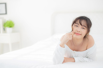 Portrait beautiful young asian woman smile while wake up healthy and wellness at morning in the bedroom, beauty asia girl lying skin care and makeup cosmetic with happy, lifestyle and relax concept.