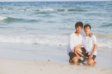 Fototapeta na wymiar Young asian couple gay smiling romantic drawing word text love together on sand in vacation, homosexual happy and fun with love sitting on sand at the beach in travel summer, LGBT legal concept.