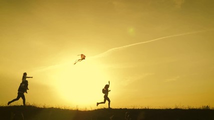 Happy family playing with a kite while on meadow, sunset, in summer day. Funny family time. Happy little girl launch a kite with parents. Mom, Dad and daughter are happy together. - Powered by Adobe