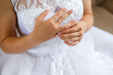 Close-up of a bride in a white wedding dress straightens her wedding ring
