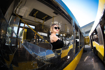 young beautiful woman posing on broken bus window with sunglasses