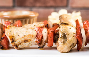 Grilled Chicken and Vegetable Skewers with bell peppers, zucchini, onion and mushrooms on white background, top view, copy space. Meat and vegetables kebabs on skewers.