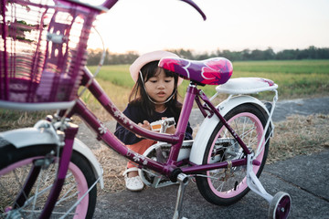 Obraz premium portrait of a child try to fix her own bicycle outdoor
