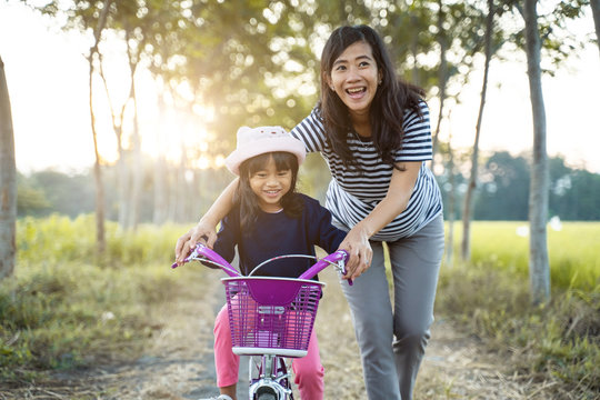 mom teach her toddler daughter to learn bicycle outdoor