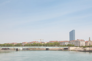 Obraz premium Pont de la Guillotiere bridge in Lyon, France over a panorama of the riverbank of the Rhone river (Quais de Rhone) with older buildings and a modern skyline in background
