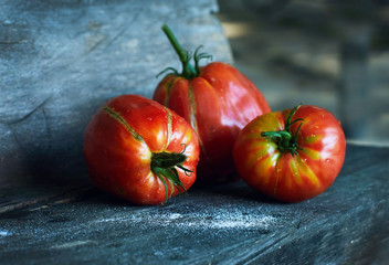 Three big red ripe organic tomato on the dark wood