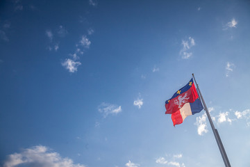 Ville de Lyon city coat of arms on a flag waiving in front of the French flag in Lyon, France. These are the historic heraldic symbol of the city, dating from the medieval time