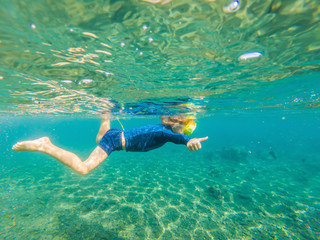Happy family - active kid in snorkeling mask dive underwater, see tropical fish in coral reef sea...