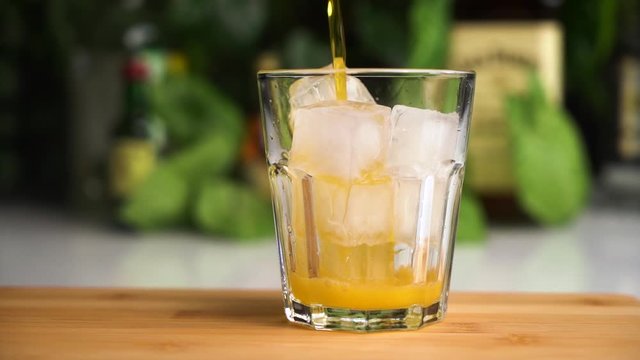 Orange soda slow motion fill glass with ice. Fanta soda drink