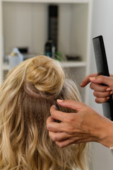 Fototapeta premium Hairtician builds upper bun. Hairstyle on bob. Hairdressing services. Creating evening hairstyles fashionable stylish women's hairstyles. Process of hair styling. Courses in hairdressing. Beauty salon