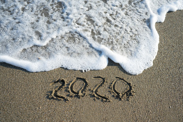New year 2020 on sandy beach with waves