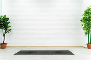 Empty room with yoga mat on floor with white wall. Can use for backdrop and background.