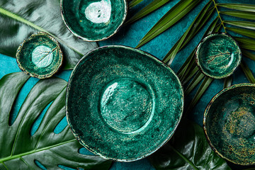 Background with empty green plates over tropical palm tree leaves and monstera