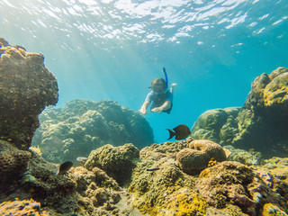 Naklejka na ściany i meble Happy man in snorkeling mask dive underwater with tropical fishes in coral reef sea pool. Travel lifestyle, water sport outdoor adventure, swimming lessons on summer beach holiday. Aerial view from