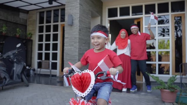 indonesian family decorating bicycle with flag and bow for indonesia independence day celebration party