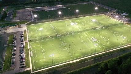 Four Soccer Football Fields Orbit Aerial, Illuminated With Night Games in Progress