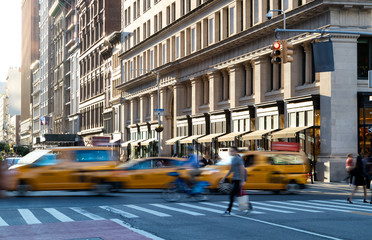 Yellow taxis in motion on 5th Avenue through Midtown Manhattan New York City