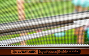 Open window with mesh screen covering and printed child warning.  