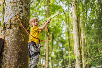 Little boy in a rope park. Active physical recreation of the child in the fresh air in the park. Training for children