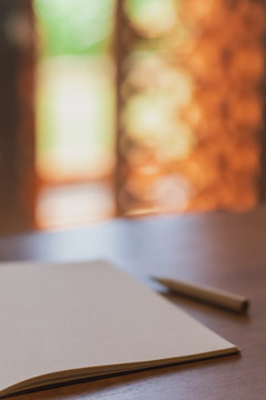 Notebooks and pencil on wooden table with beautiful blurred bokeh background