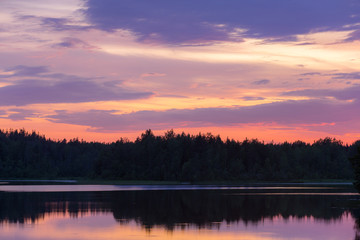 Fototapeta na wymiar dramatic sunset over a forest lake