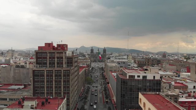 Aerial view of Zocalo in Mexico City, the Monumental Flag and the Cathedral. Drone flying forward and descending