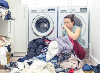 tired unhappy woman housewife in a laundry room near washing machine