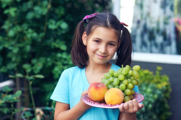 Portrait of a beautiful girl with peaches . The child holds fresh ripe fruit in his hands