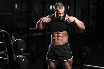Muscular athletic bodybuilder fitness model checking abs after exercises in gym. Concept sport photo