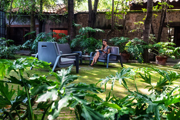 Woman reading a book on a tropical garden