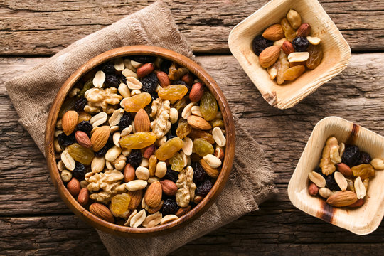 Healthy trail mix snack made of nuts (walnut, almond, peanut) and dried fruits (raisin, sultana) in wooden bowl, photographed overhead (Selective Focus, Focus on the trail mix in the big bowl)