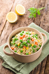 Fresh homemade cooked white quinoa with colorful vegetables (green peas, sweet corn kernels, green beans, carrots) and parsley in bowl (Selective Focus, Focus on the front of the dish)
