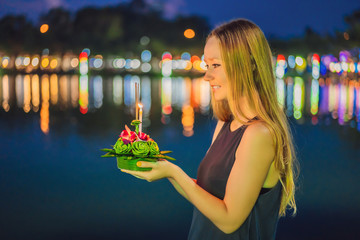 A female tourist holds the Loy Krathong in her hands and is about to launch it into the water. Loy...