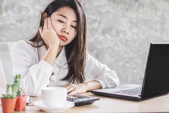 unmotivated Asian woman worker lazy and bored to work wasting time at office  desk Stock Photo