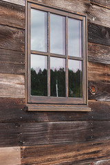 large window on a wooden building reflecting the sky on a cloudy overcast day