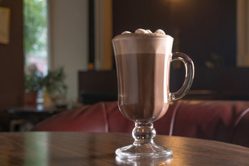 cup of carob, cacao or coffee with milk froth on restaurant table