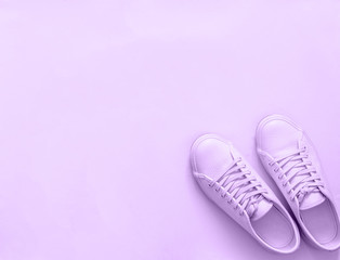 Violet leather sneakers on violet background. Pair of violet sport shoes or sneakers with copy...