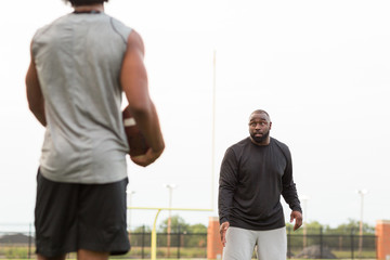 American Football coach training a young athlete.