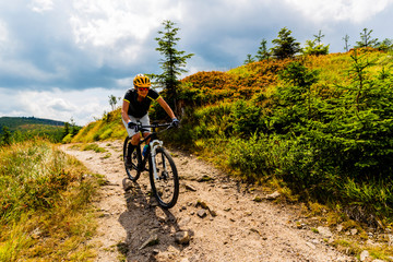 Mountain biking woman riding on bike in summer mountains forest landscape. Woman cycling MTB flow...