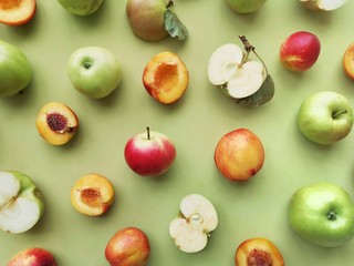 green apples and peaches on a green background flat layout top view. Fruits pattern. 