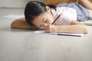 ASian girl sleeping on the floor while doing homework at home, lifestyle concept.