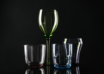 Set of different colorful empty glasses on black background