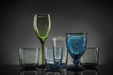 Set of different colorful empty glasses on table against grey background