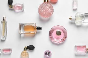 Different luxury perfume bottles on white background, top view