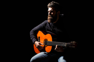 Bearded guitarist plays. Play the guitar. Beard hipster man sitting in a pub. Live music. Guitars and strings. Bearded man playing guitar, holding an acoustic guitar in his hands. Music concept