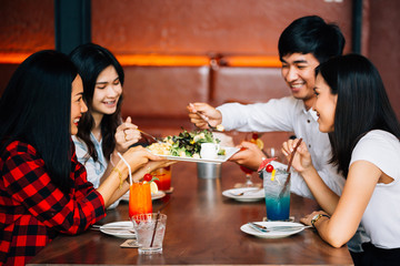 Group of Asian happy and smiling young man and women having a meal together with enjoyment and happiness