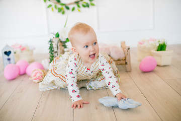 Cute little girl in a dress with a flower print  in the Easter decorations in the studio. Little...