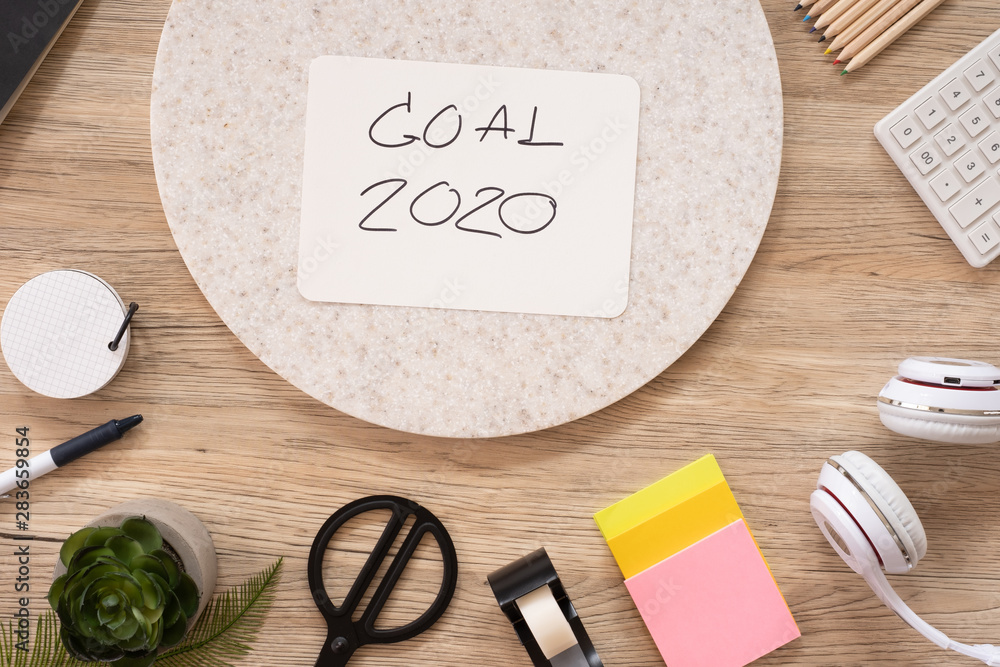 Aufkleber new year goal 2020 on paper top view at wood office table with stationery stuff.business vision.