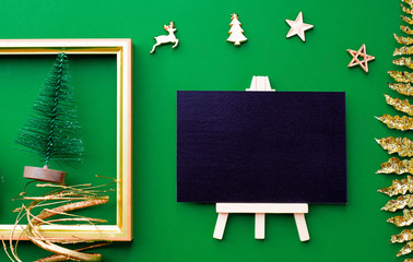 Blackboard top view with gold christmas and new year decoration ornament stuff on green paper background.celebrate hoiday greeting card.mock up for display of design.